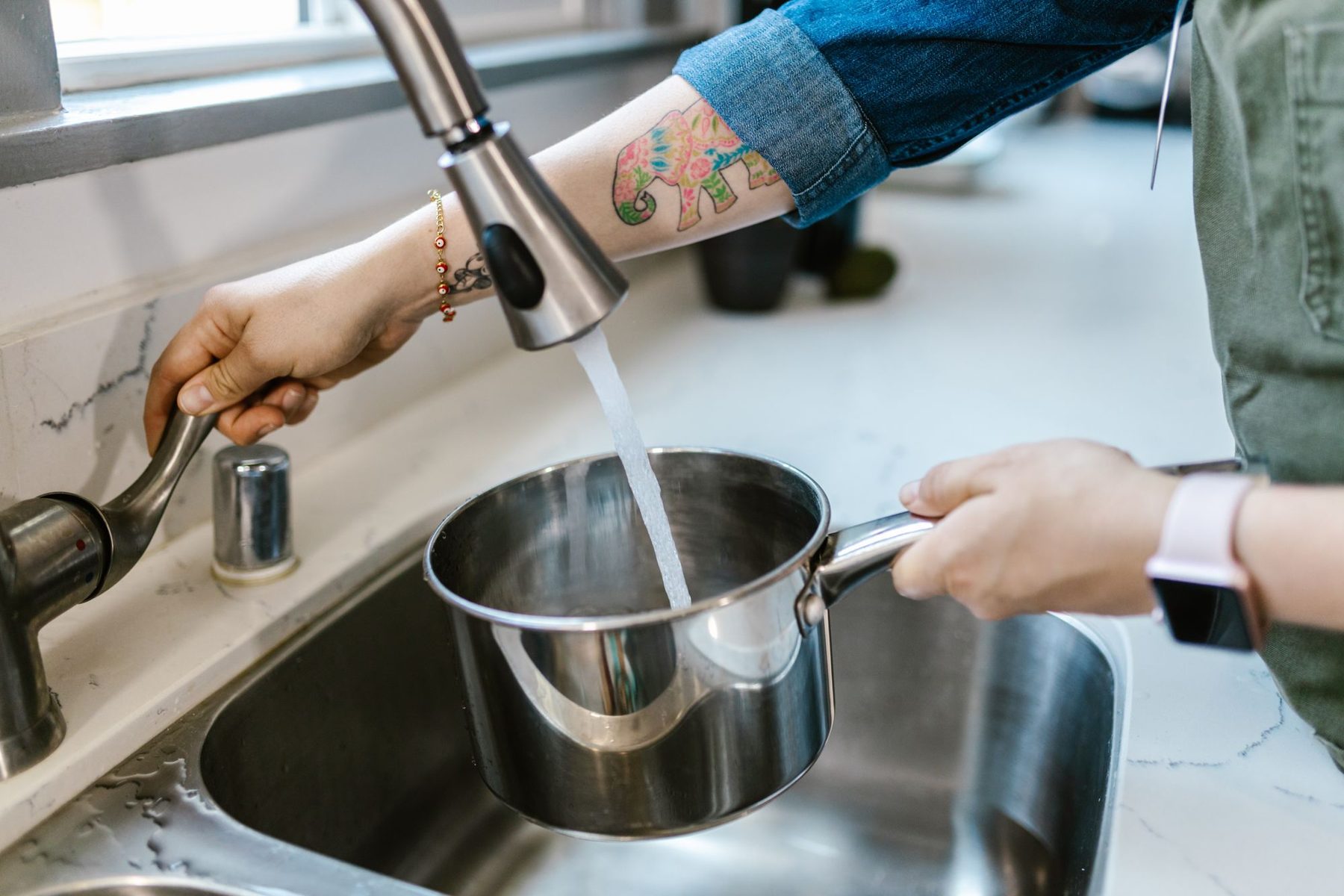 A cooking pot being filled with water at the tap